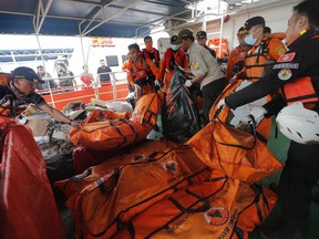 Rescuers load body bags containing debris and body parts onto a rescue ship during the search operations for victims of the crashed Lion Air plane in the waters of Ujung Karawang, Indonesia, Tuesday, Oct. 30, 2018.