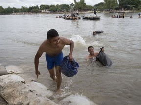 Central American migrants reach the shore on the Mexican side of the Suchiate River after wading across, on the the border between Guatemala and Mexico, in Ciudad Hidalgo, Mexico, Saturday, Oct. 20, 2018.