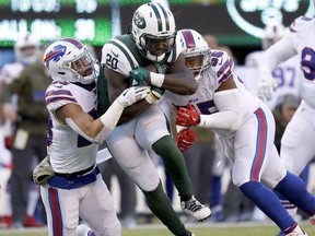 Isaiah Crowell of the New York Jets is tackled by Micah Hyde and Jerry Hughes of the Buffalo Bills during the third quarter at MetLife Stadium on November 11, 2018 in East Rutherford, New Jersey.