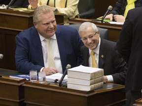 Ontario Finance Minister Vic Fedeli (R) rises in the legislature at Queen's Park Thursday afternoon, to unveil his economic outlook for the province. Premier Doug Ford looks on.
