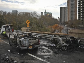 Authorities investigate the scene of a fiery crash involving three vehicles on the Brooklyn Bridge, Wednesday morning, Nov. 21, 2018, in New York. Fire Department officials said six people were injured, and one person was killed.   (AP Photo/Bebeto Matthews)