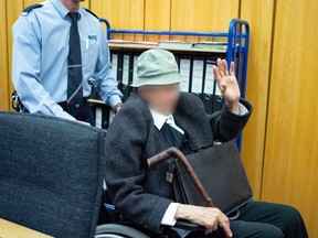 A justice officer pushes the 94-years-old defendant (R), a former SS guard, in a wheelchair to the courtroom for his trial at the regional court in Muenster, western Germany, on November 6, 2018. His face is blurred on court order.