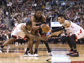 Miami Heat guard Dwyane Wade, centre, gathers a loose ball between Toronto Raptors Kawhi Leonard, left, and Danny Green during second half in Toronto on Sunday. THE CANADIAN PRESS/Chris Young