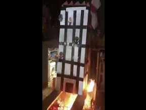 In this grab taken from video, made available on Tuesday, Nov. 6, 2018, people place a model of Grenfell Towers onto a bonfire, in London.