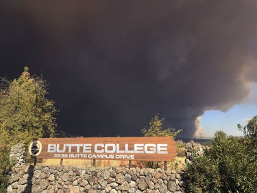 Smoke from the Camp Fire, burning in the Feather River Canyon near Paradise, Calif., darkens the sky above the Butte College sign in Oroville, Calif., Thursday, Nov. 8, 2018.