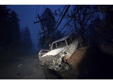 A scorched vehicle rests on a roadside as the Camp Fire tears through Paradise, Calif., on Thursday, Nov. 8, 2018.