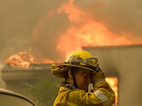 A firefighter keeps watch as the wildfire burns a home near Malibu Lake in Malibu, Calif., Friday, Nov. 9, 2018.   About two-thirds of the city of Malibu was ordered evacuated early Friday as a ferocious wildfire roared toward the beachside community that is home to about 13,000 residents, some of them Hollywood celebrities.