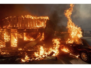 Flames consume a car and building as the Camp Fire tears through Paradise, Calif., on Thursday, Nov. 8, 2018.