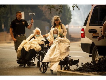 Emergency personnel evacuate patients as the Feather River Hospital burns while the Camp Fire rages through Paradise, Calif., on Thursday, Nov. 8, 2018.