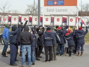 Striking Canada Post workers walk the picket line in front of the Saint-Laurent sorting facility in Montreal on Thursday, Nov. 15, 2018.