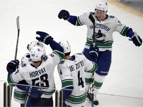 Vancouver Canucks defenseman Troy Stecher, top right, joins his teammates to celebrate a goal by centre Bo Horvat.