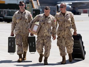 A Canadian Forces members, from 450 Tactical Helicopter Squadron at Canadian Forces Base Petawawa, arrive to help with the loading of a CH-147F Chinook helicopter, left, at CFB Trenton in Trenton, Ont., on Tuesday, July 3, 2018. The helicopter has been used during Canada's UN mission in Mali.