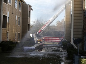 Firefighters put out hot spots during an apartment fire at the intersection of Interstate 635 and Ferguson Rd. in Dallas on Wednesday, Nov. 21, 2018. (Nathan Hunsinger/The Dallas Morning News via AP)