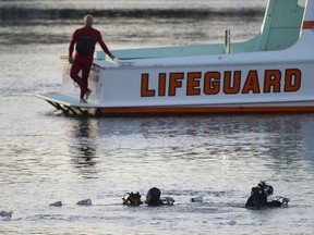 In this Thursday, April 9, 2015 photo, divers emerge from the water as debris believed to be from a car floats to the surface where a car went off the berth and into the water at the San Pedro Slip, across from Ports O'Call in San Pedro, Calif. U.S. prosecutors have charged an Egyptian father with fraudulently collecting insurance payouts after driving his family off a Los Angeles pier and killing his two severely autistic sons. Prosecutors said Tuesday, Nov. 13, 2018, that Ali Elmezayen had purchased $6 million in insurance policies to cover his family in the event of an accidental death two years before the 2015 deaths.