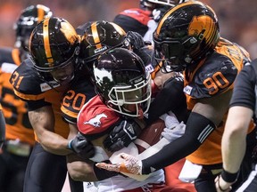 Calgary Stampeders' Don Jackson, front, is tackled by B.C. Lions' Otha Foster III (31), Bo Lokombo (20) and Davon Coleman (90) during the first half of a CFL football game in Vancouver, on Saturday November 3, 2018.