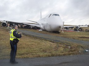 A Halifax Regional Police officers stands near a SkyLease Cargo plane that skidded off a runway at Halifax Stanfield International Airport and stopped near a road early on Wednesday, Nov. 7, 2018. The airport activated its emergency operations centre and suspended all flights after the incident where the 747 cargo plane with five people on board went off the runway.