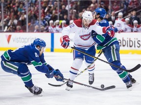 Montreal Canadiens' Jonathan Drouin, centre, is checked by Vancouver Canucks' Michael Del Zotto, right, as Tyler Motte, left, reaches for the puck in Vancouver on Saturday, Nov. 17, 2018.