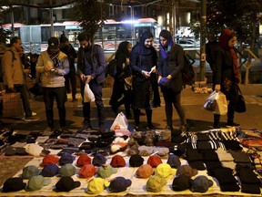 Pedestrians look at items of a vendor in downtown Tehran, Iran, Monday, Nov. 5, 2018. Iran greeted the re-imposition of U.S. sanctions on Monday with air defense drills and a statement from President Hassan Rouhani that the nation faces a "war situation," raising Mideast tensions as America's maximalist approach to the Islamic Republic takes hold.