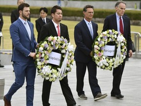 MLB All-Star team, from left, Mitch Haniger of the Seattle Mariners, Kenta Maeda of the Los Angeles Dodgers, and manager Don Mattingly lay a wreath at the cenotaph in the Peace Memorial Park which commemorates the victims of the atomic bombings in 1945, in Hiroshima, western Japan, Monday, Nov. 12, 2018. (Kyodo News via AP) ORG XMIT: TKSK821