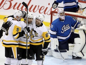 Pittsburgh Brian Dumoulin (8), Zach Aston-Reese (46) and Phil Kessel (81) celebrate after Aston-Reese scored against Winnipeg Jets goaltender Connor Hellebuyck (37) during third period NHL action in Winnipeg, Tuesday, Nov. 27, 2018.