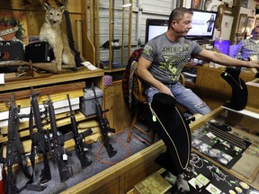In this Oct. 20, 2017 file photo, Johnny's Auction House owner John West prepares items, including a line of assault rifles at left, for auction where the company handles gun sales for both civilians and a half dozen police departments and the Lewis County Sheriff's Office, in Rochester, Wash.