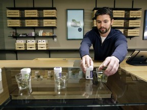 Sam Barber, president and CEO of the Cultivate dispensary, arranges smokable strains of cannabis before opening on the first day of legal recreational marijuana sales, Tuesday, Nov. 20, 2018, in Leicester, Mass.