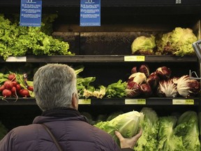 Lisa Dennis of Regent Square selects a head of green lettuce from the vegetable shelves at the East End Food Co-op Federal Credit Union Tuesday, Nov. 20, 2018, in Pittsburgh. Due to a recent consumer alert regarding a multi state E.Coli outbreak the Co-op has replaced their fresh and bagged romaine lettuce with blue signs reading, "The CDC has issued a Consumer Alert for romaine lettuce due to a multi state E.Coli outbreak."