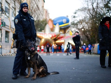 A New York Police Department officer and a K9 unit stand guard as people arrive to watch the 92nd annual Macy's Thanksgiving Day Parade in New York, Thursday, Nov. 22, 2018.