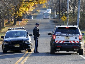 Colts Neck and Howell police officers block the road Wednesday, Nov. 21, 2018, in Colts Neck, N.J., leading to the scene of a fatal fire that killed two children and two adults. (AP Photo/Noah K. Murray)