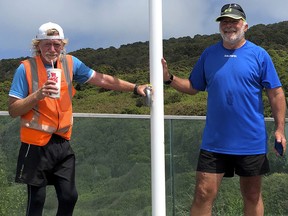 In this Wednesday, Nov. 21, 2018 photo, Perry Newburn, left, stands with support crew member Graeme Calder at Stirling Point in Bluff at the bottom of the South Island of New Zealand. (Kashif Shuja via AP)