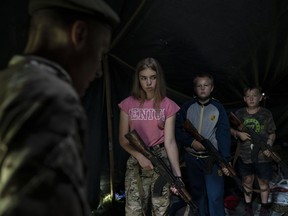 In this July 28, 2018 photo, participants of the "Temper of will" summer camp, organized by the nationalist Svoboda party, hold their AK-47 riffles as they receive instructions during a tactical exercise in a village near Ternopil, Ukraine. Campers as young as 8 years old practice using assault rifles. They are taught to shoot to kill Russians and their sympathizers.