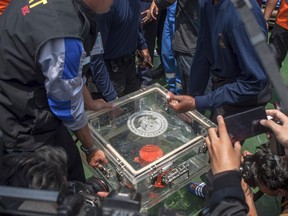 In this Thursday, Nov. 1, 2018, file photo, members of the National Transportation Safety Committee lift a box containing the flight data recorder from a crashed Lion Air jet onboard a rescue ship anchored in the waters of Tanjung Karawang, Indonesia.