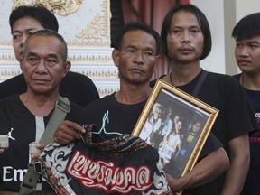 In this Thursday, Nov. 15, 2018, photo, relatives of 13-year-old Thai kickboxer Anucha Tasako hold his boxing shorts and a portrait during his funeral services in Samut Prakan province.
