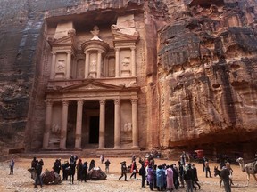 In this Feb. 13, 2017, file photo, tourists brave a rare rainstorm in plastic ponchos to peer at the Treasury, Jordan's most famous archaeological monument leftover from the Nabatean civilization in the kingdom's Petra archaeological park. Flash floods caused by heavy rain across Jordan killed people Friday, Nov. 9, 2018 and forced hundreds of tourists to seek higher ground in the kingdom's ancient city of Petra, the government spokeswoman said.