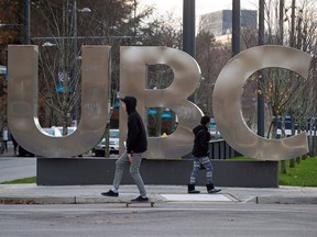 A man on a skateboard and a young woman pass large letters spelling out UBC at the University of British Columbia in Vancouver on November 22, 2015. (THE CANADIAN PRESS/Darryl Dyck)