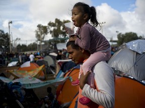 A man carries a girl on his shoulders at a migrant shelter in Tijuana, Mexico, Thursday, Nov. 22, 2018.