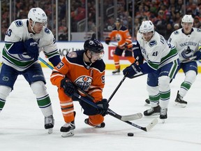The Edmonton Oilers' Ryan Nugent-Hopkins  battles the Vancouver Canucks' Bo Horvat and Loui Eriksson during second period NHL action at Rogers Place, in Edmonton on Thursday, Dec. 27, 2018.