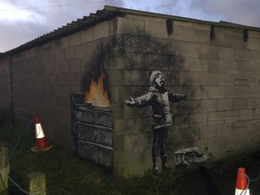 An artwork by street artist and social commentator Banksy is seen on a garage in Port Talbot, Wales, Wednesday Dec. 19, 2018. (Twitter/@RHoneyJones via AP)