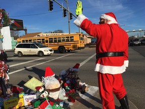 In this Dec. 18, 2018 photo, Jimmy Izbinski, wearing a Santa suit, waves to motorists passing the Christmas weed in Toledo, Ohio. (AP Photo/John Seewer)