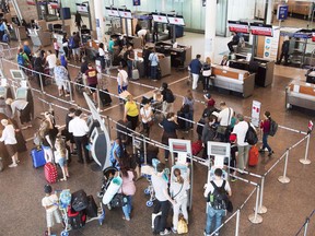 Passengers wait to check in at Trudeau Airport in Montreal on July 19, 2017.