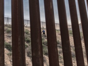 A Honduran migrant w climbs an embankment after jumping over the U.S. border wall from Tijuana, Mexico, to San Diego, Calif., as seen from Tijuana, Mexico, Friday, Dec. 21, 2018.