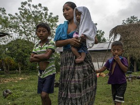 Claudia Maquin, 27, walks with her three children, Abdel Johnatan Domingo Caal Maquin, 9, left, Angela Surely Mariela Caal Maquin, 6 months, middle, and Elvis Radamel Aquiles Caal Maquin, 5, right, as they leave Domingo Caal Chub's house, Claudia's father in law, in Raxruha, Guatemala, Saturday, Dec. 15, 2018. (AP Photo/Oliver de Ros)