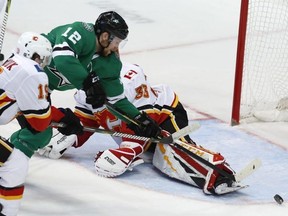 Stars centre Radek Faksa (12) gets the puck past Flames goaltender David Rittich (33) and Matthew Tkachuk (19) for a goal during second period NHL action in Dallas, Tuesday, Dec. 18, 2018.
