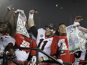 In this Jan. 1, 2018 file photo Georgia players hold up newspapers as they celebrate after they defeated Oklahoma 54-48 in overtime in the Rose Bowl in Pasadena, Calif. (AP Photo/Jae C. Hong, file)