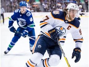 Edmonton Oilers' Connor McDavid, front right, skates with the puck past Vancouver Canucks' Elias Pettersson, of Sweden, during third period NHL hockey action in Vancouver on Sunday, Dec. 16, 2018.