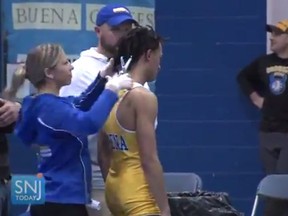 In this image taken from a Wednesday, Dec. 19, 2018 video provided by SNJTODAY.COM, Buena Regional High School wrestler Andrew Johnson gets his hair cut courtside minutes before his match in Buena, N.J., after a referee told Johnson he would forfeit his bout if he didn't have his dreadlocks cut off. Johnson went on to win the match after a SNJ Today reporter tweeted video if the incident, the state's Interscholastic Athletic Association says they are recommending the referee not be assigned to any event until the matter has been reviewed more thoroughly.