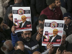 In this Nov. 16, 2018 file photo, members of Arab-Turkish Media Association and friends of Washington Post columnist Jamal Khashoggi hold posters showing images of Saudi Crown Prince Muhammed bin Salman and of Khashoggi, as they attend funeral prayers in absentia for him following his killing the previous month in the Saudi Arabia consulate, in Istanbul.