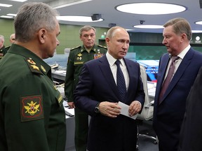 Russian Defense Minister Sergei Shoigu, left, Russian President Vladimir Putin, centre, Chief of General Staff of Russia Valery Gerasimov, background centre, and special representative on questions of ecology and transport, Sergei Ivanov, right, talk to each other as they come to oversee the test launch of the Avangard hypersonic glide vehicle from the Defense Ministry's control room in Moscow, Russia, Wednesday, Dec. 26, 2018. (Mikhail Klimentyev, Sputnik, Kremlin Pool Photo via AP)