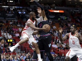 Houston Rockets guard Chris Paul, left, passes to center Clint Capela (15) as Miami Heat center Hassan Whiteside defends during the first half of an NBA basketball game, Thursday, Dec. 20, 2018, in Miami.