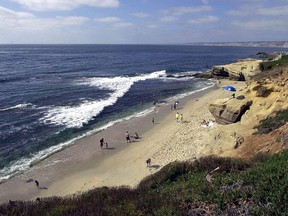 In this July 9, 2001 file photo, people stroll down the beach in the La Jolla section of San Diego, Calif. (AP Photo/Lenny Ignelzi, File)